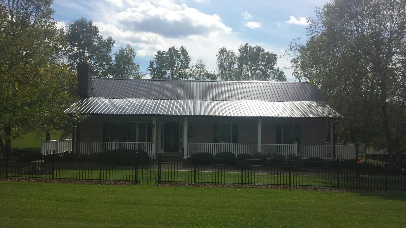 Gray metal roof on a brick ranch with a full width front porch — Gutter Guard Installation work by our crew in Marcus