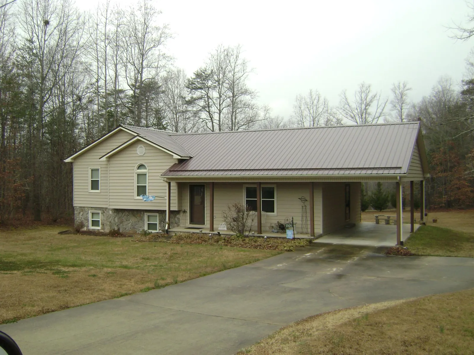 Brown metal roof on a tan split level home with an attached carport in Marcus