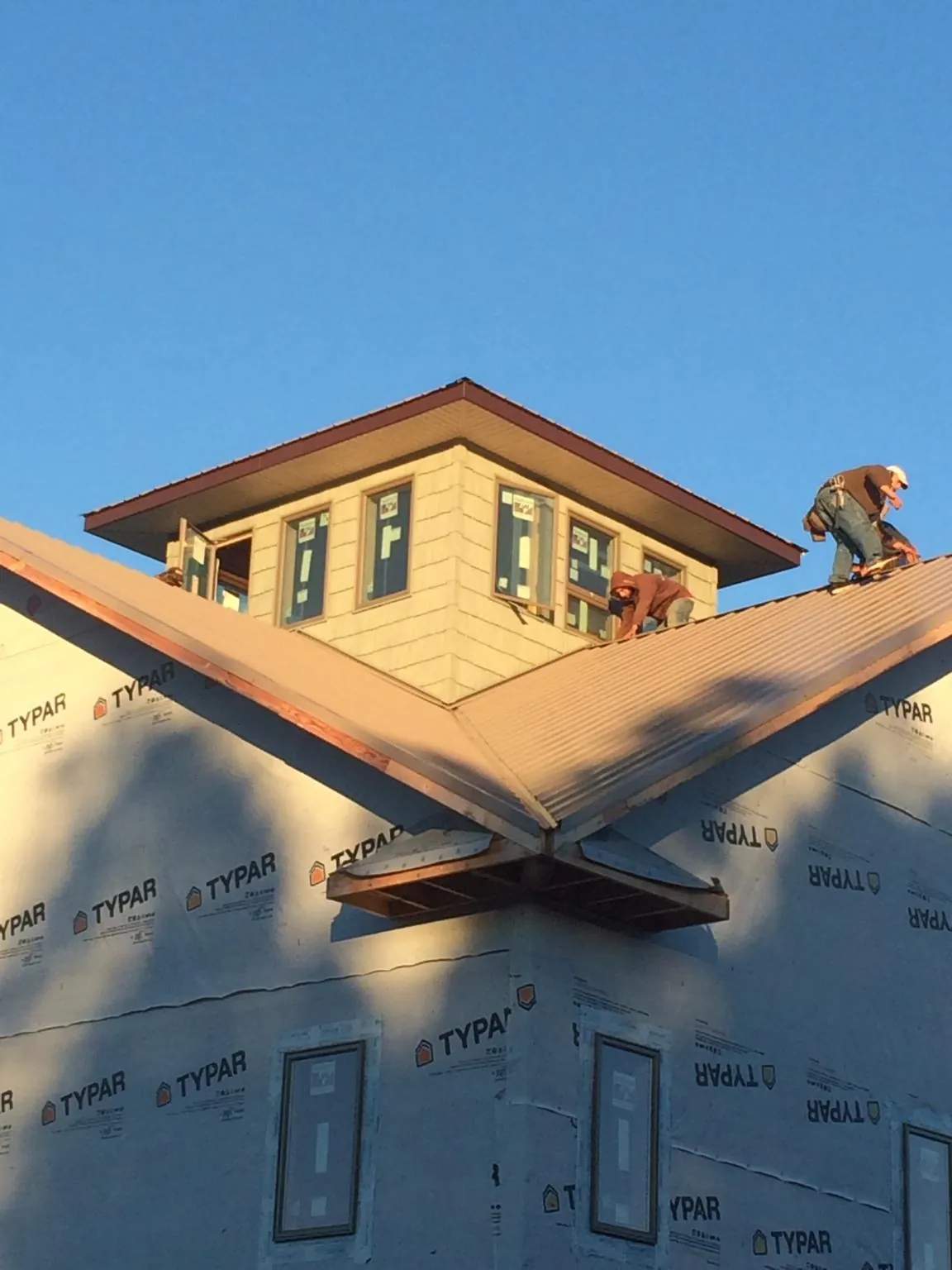 Roofers working around a rooftop cupola on a new metal roof at sunset — Roof Waterproofing in Marcus by Roofing Brothers